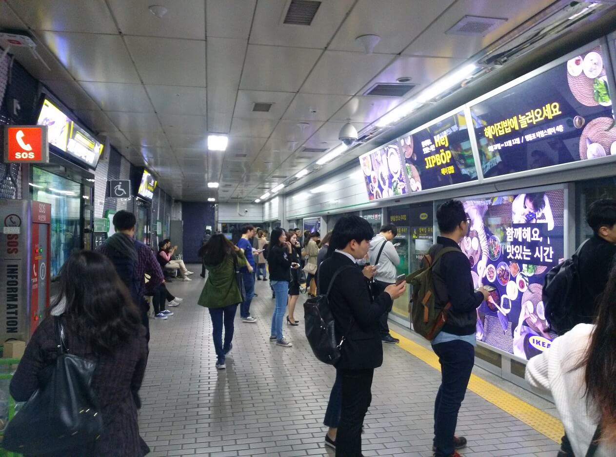 Menschen warten geduldig in einer Reihe auf die U-Bahn in Seoul